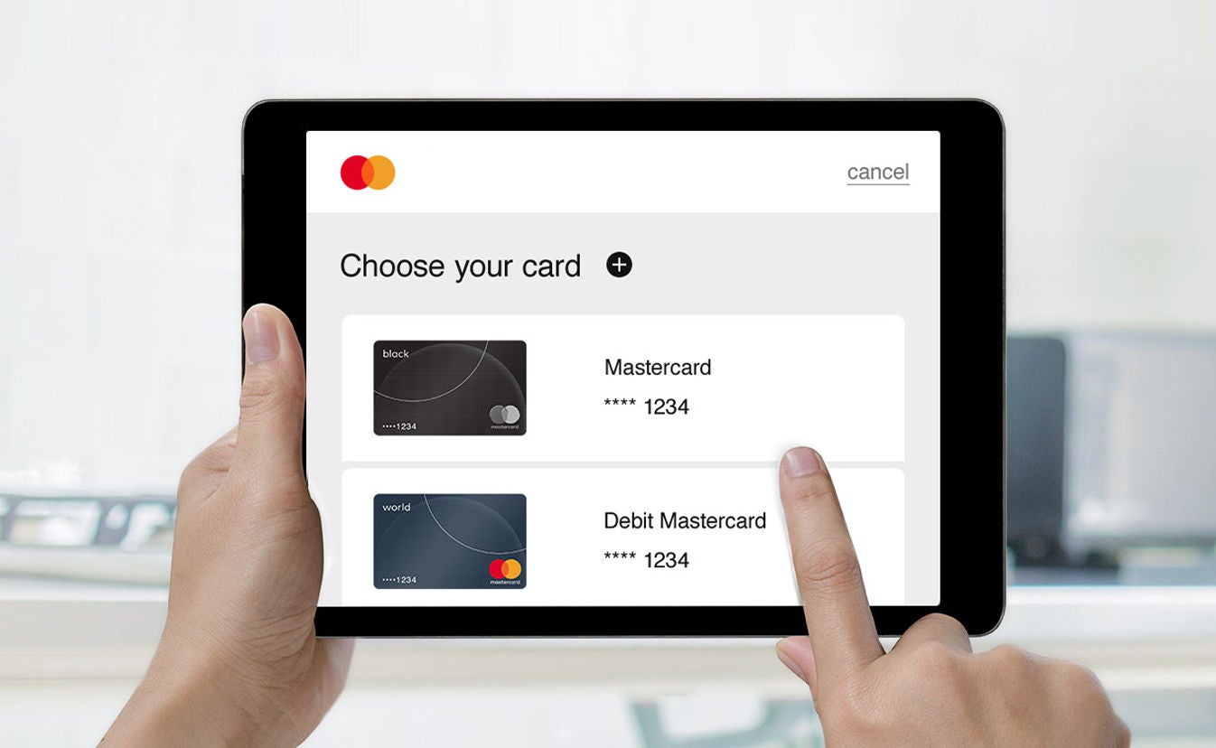 Hands holding a tablet showing a screen titled "Choose your card," displaying Mastercard options.