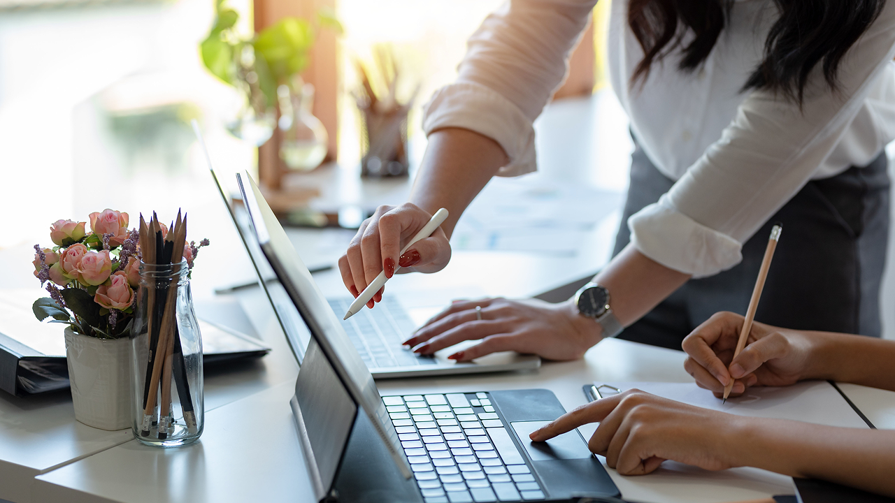 Two hands typing and writing on tablet