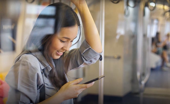 woman looking at phone riding public transport.