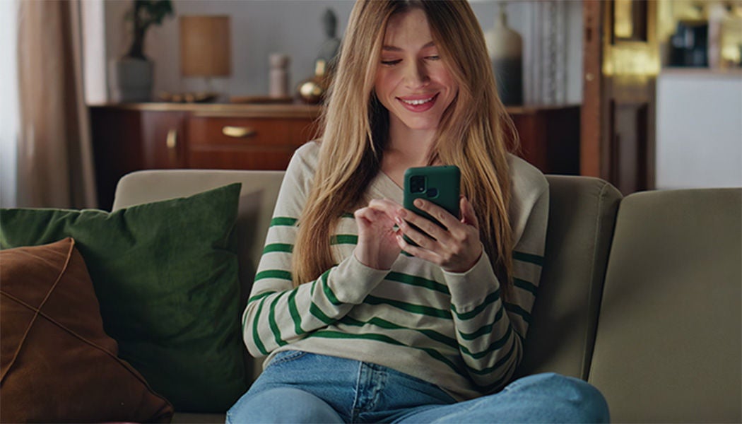 Žena koristi telefon na sofi