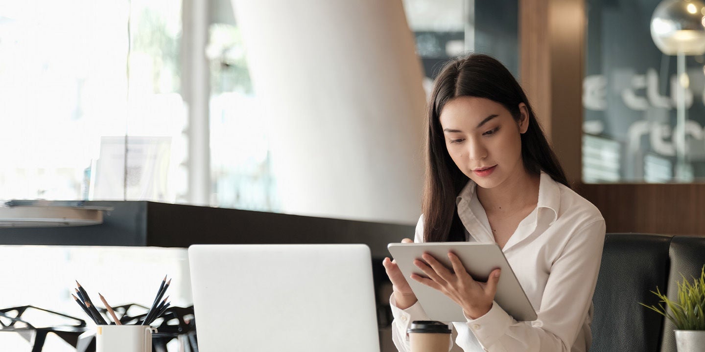 Woman using a laptop and tablet at work