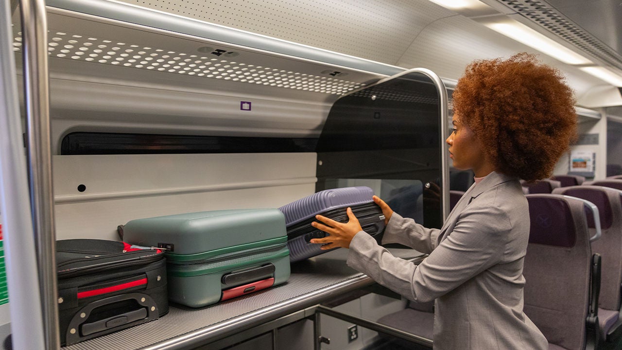 donna che sistema valigia su treno