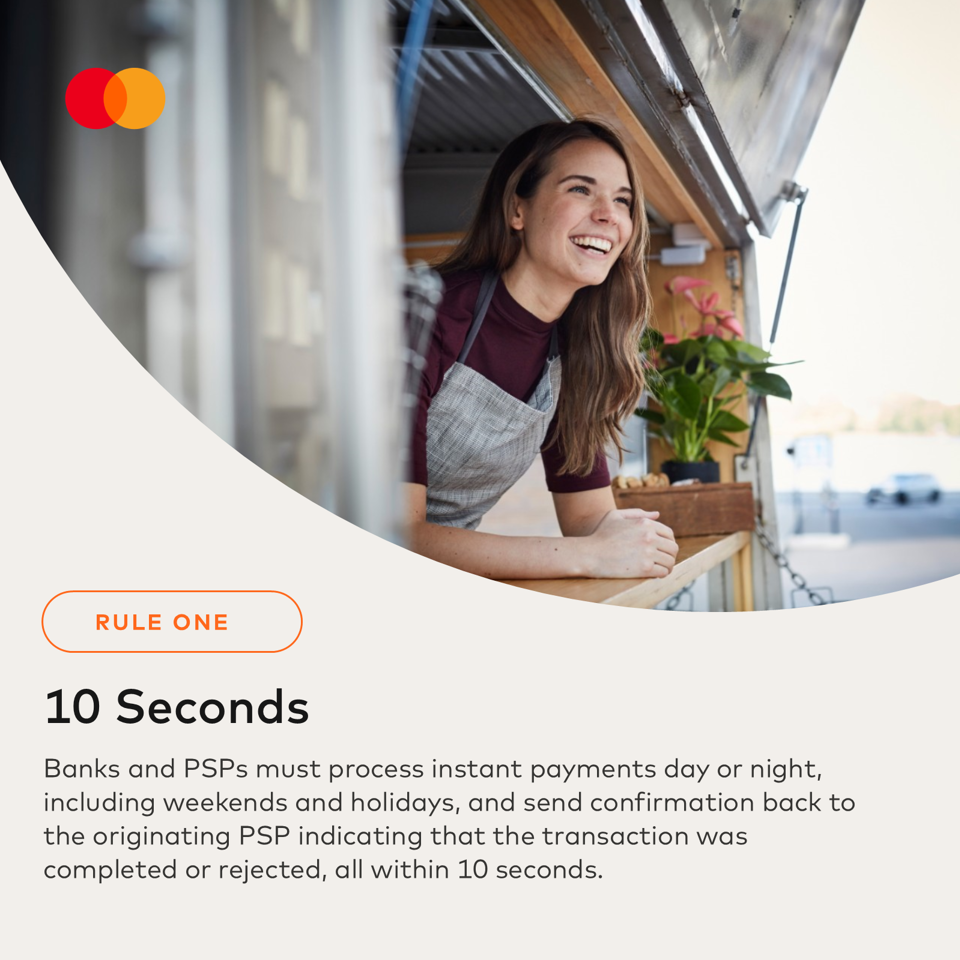 A woman in an apron smiles, leaning out of a window from a food truck.