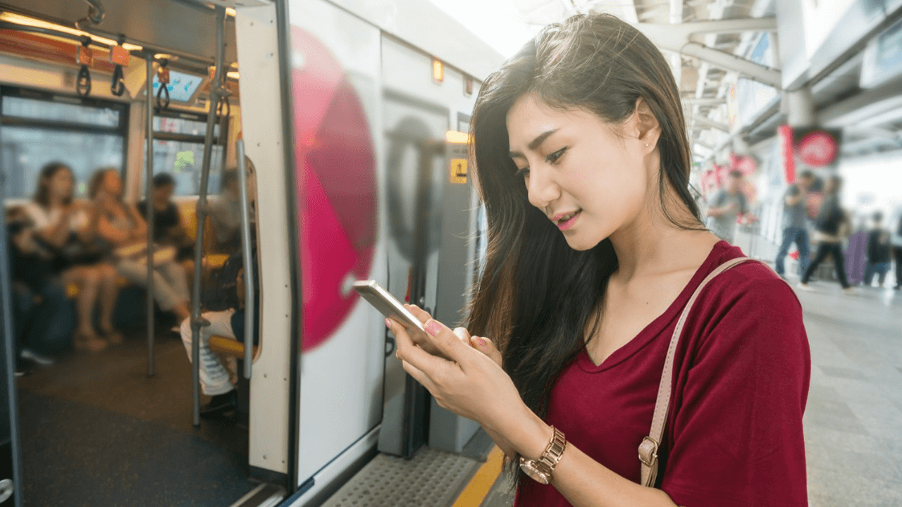 Woman check phone outside train