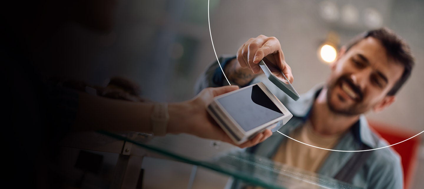 Muškarac plaća u kafiću koristeći telefon.