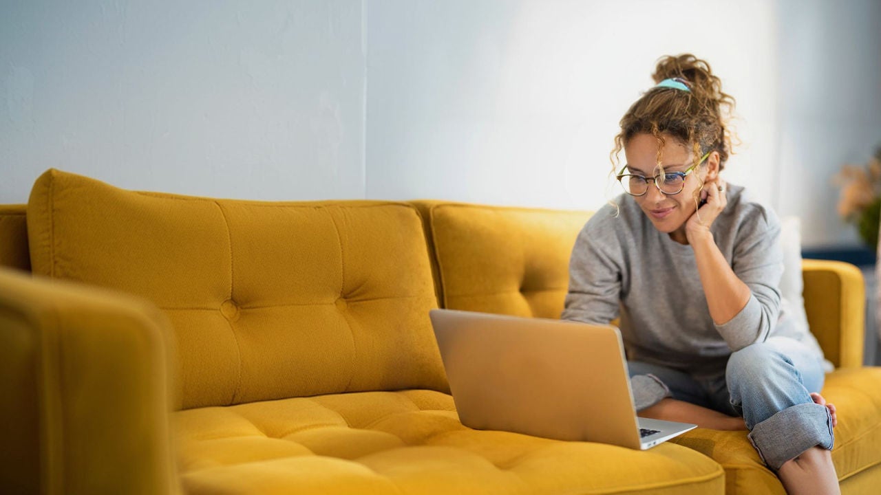 A woman sitting on a couch using a laptop