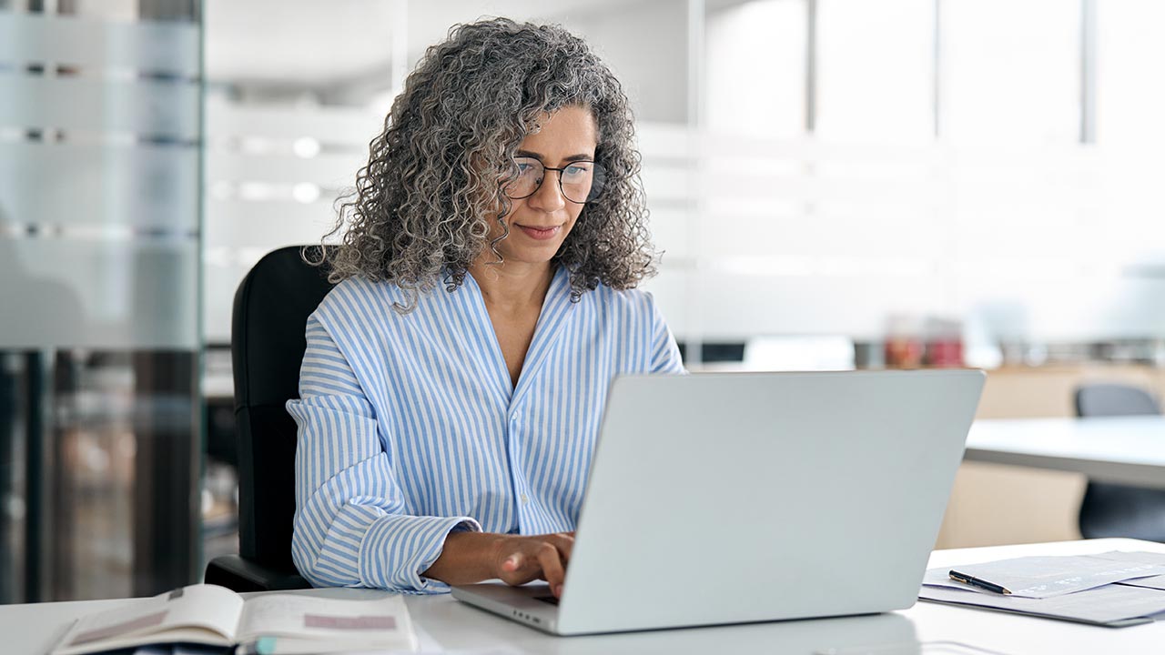 Corporate worker working on laptop in an office.