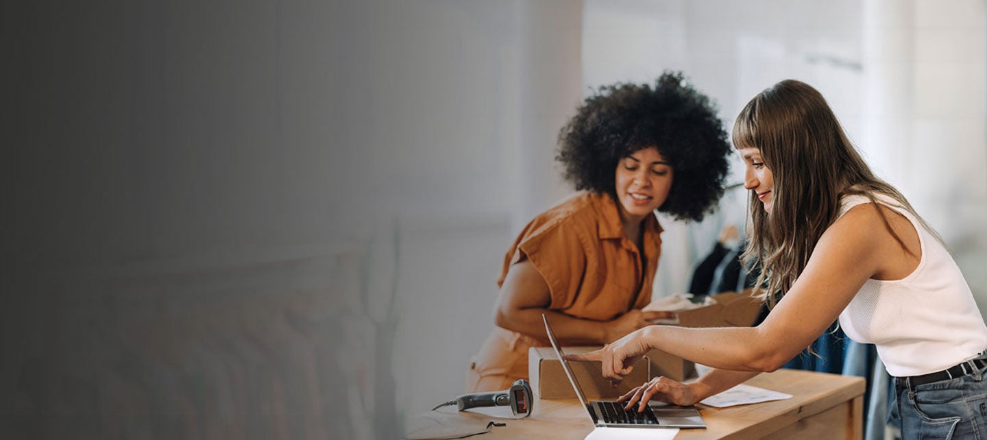 Two women using laptop.