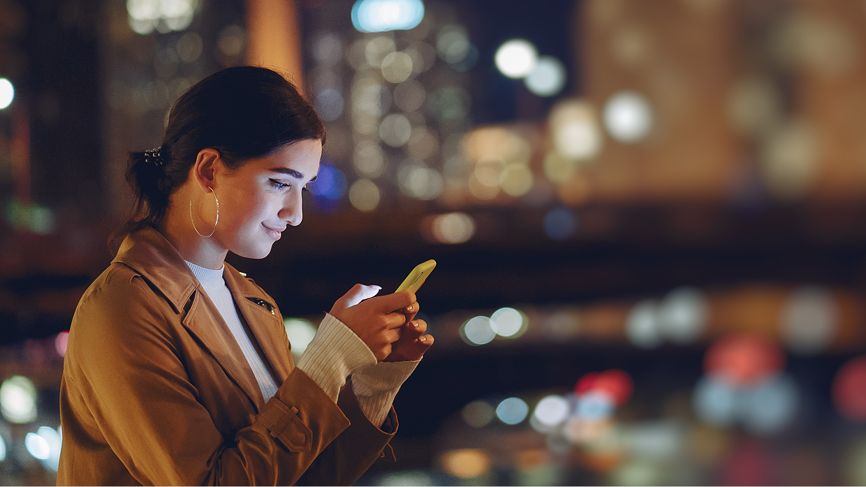 Woman on her phone at night surrounded by lights