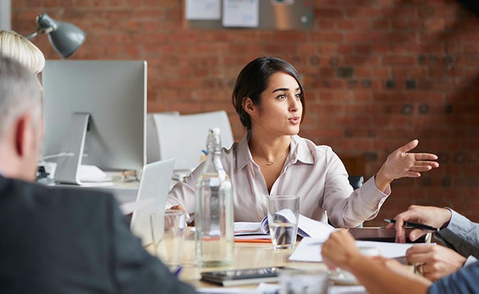 Woman speaking in a meeting at a conference table.