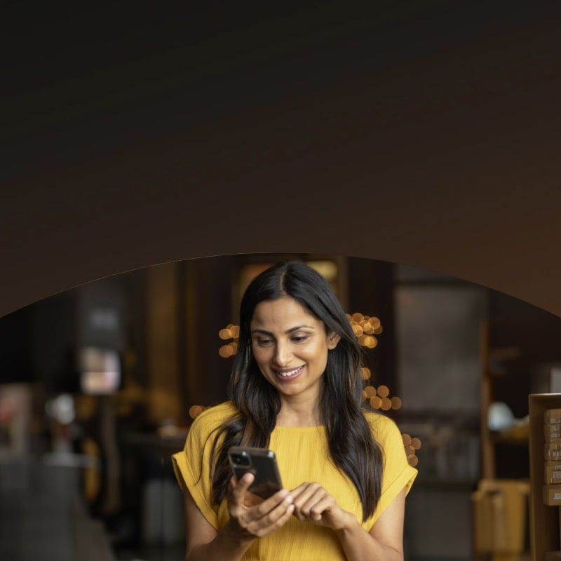 smiling woman using smartphone indoors