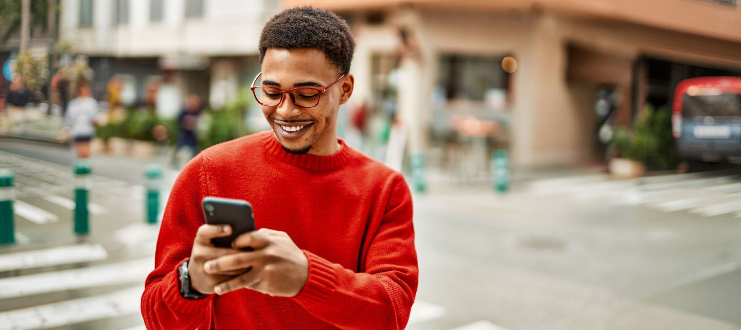Man in a red sweater smiling at phone