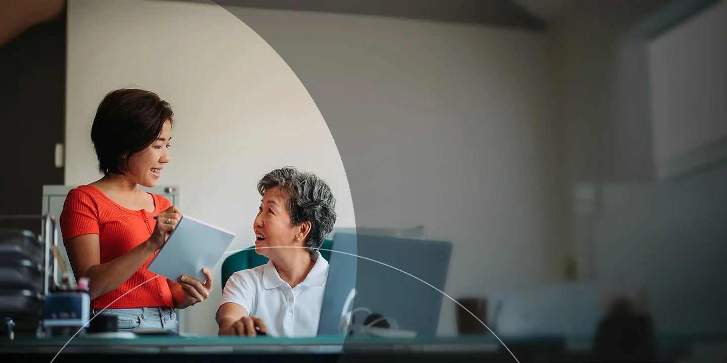 שני עובדים דנים בחשבונות עם פנקס רשימות ומחשב נייד.