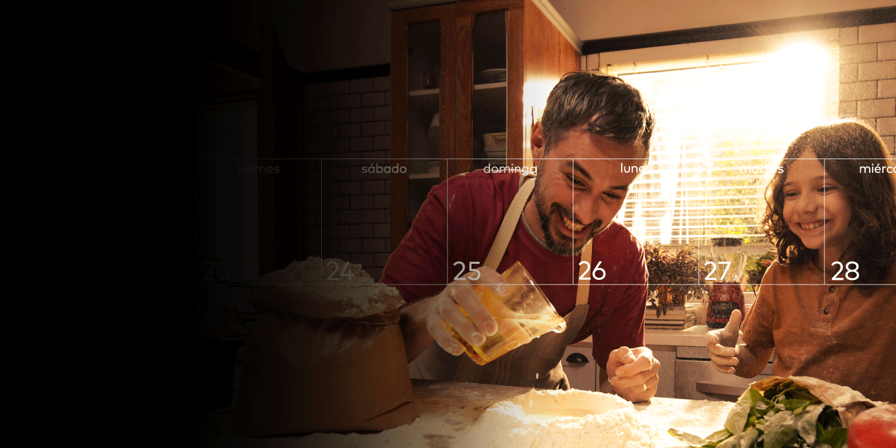 Padre e hija cocinando juntos preparando masa sobre la mesa.