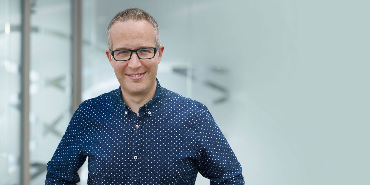 Chris Higman in einem blauen Hemd lächelt