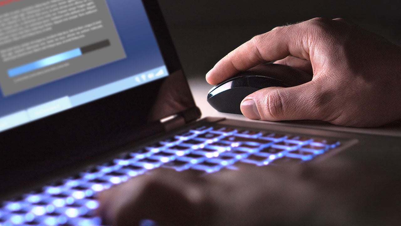 Hacker loading illegal program in a dark room.