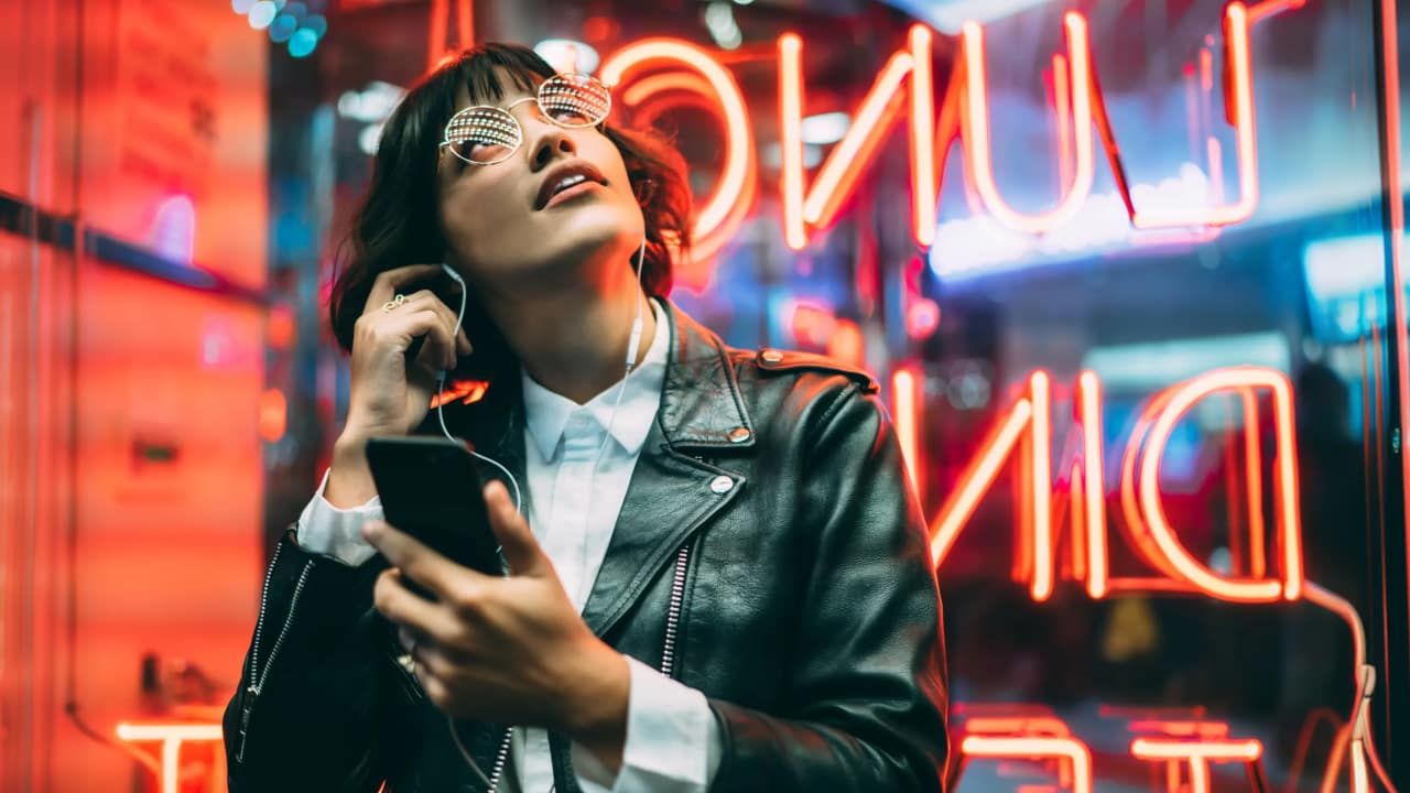 woman with earphones standing near neon signs