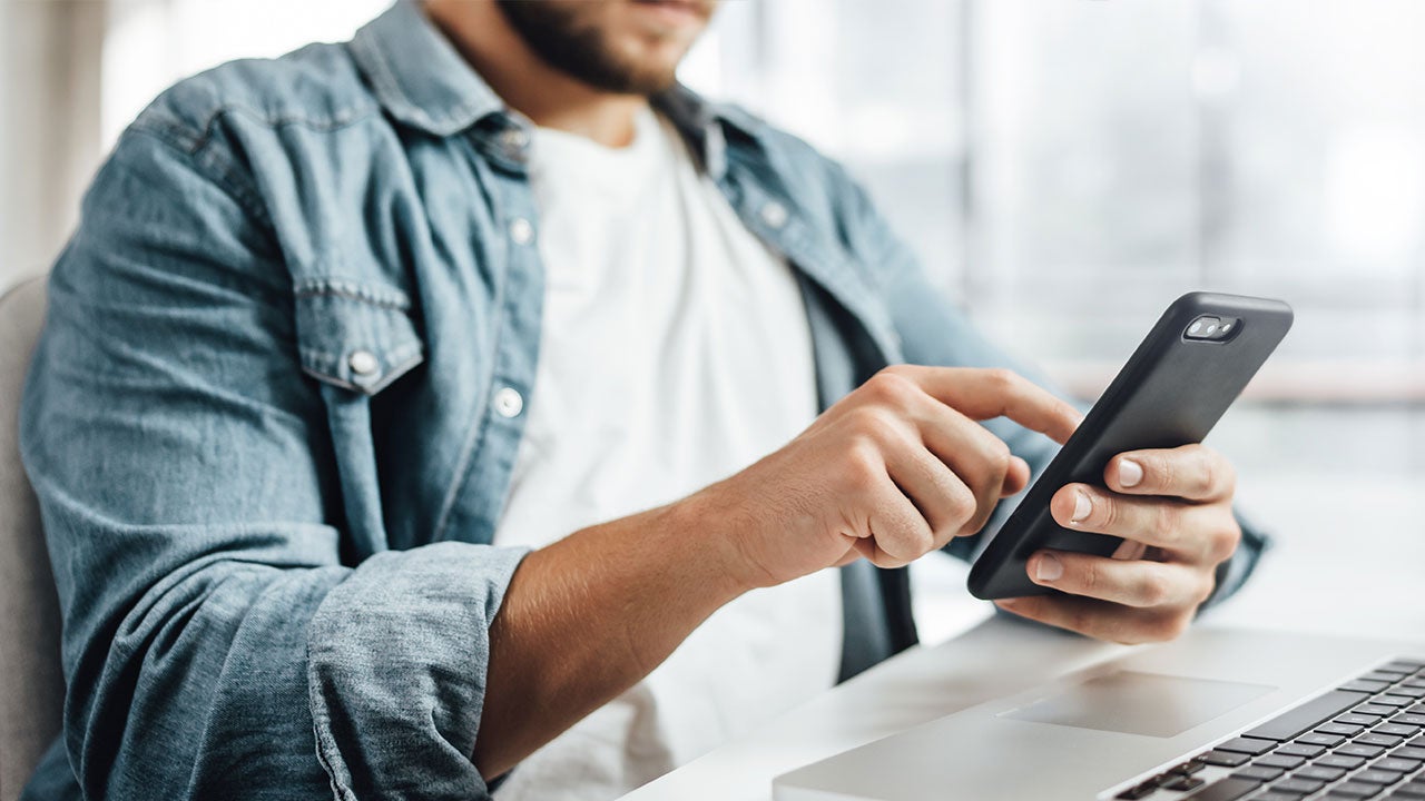 Young man with smartphone in his hands at modern sunny office.