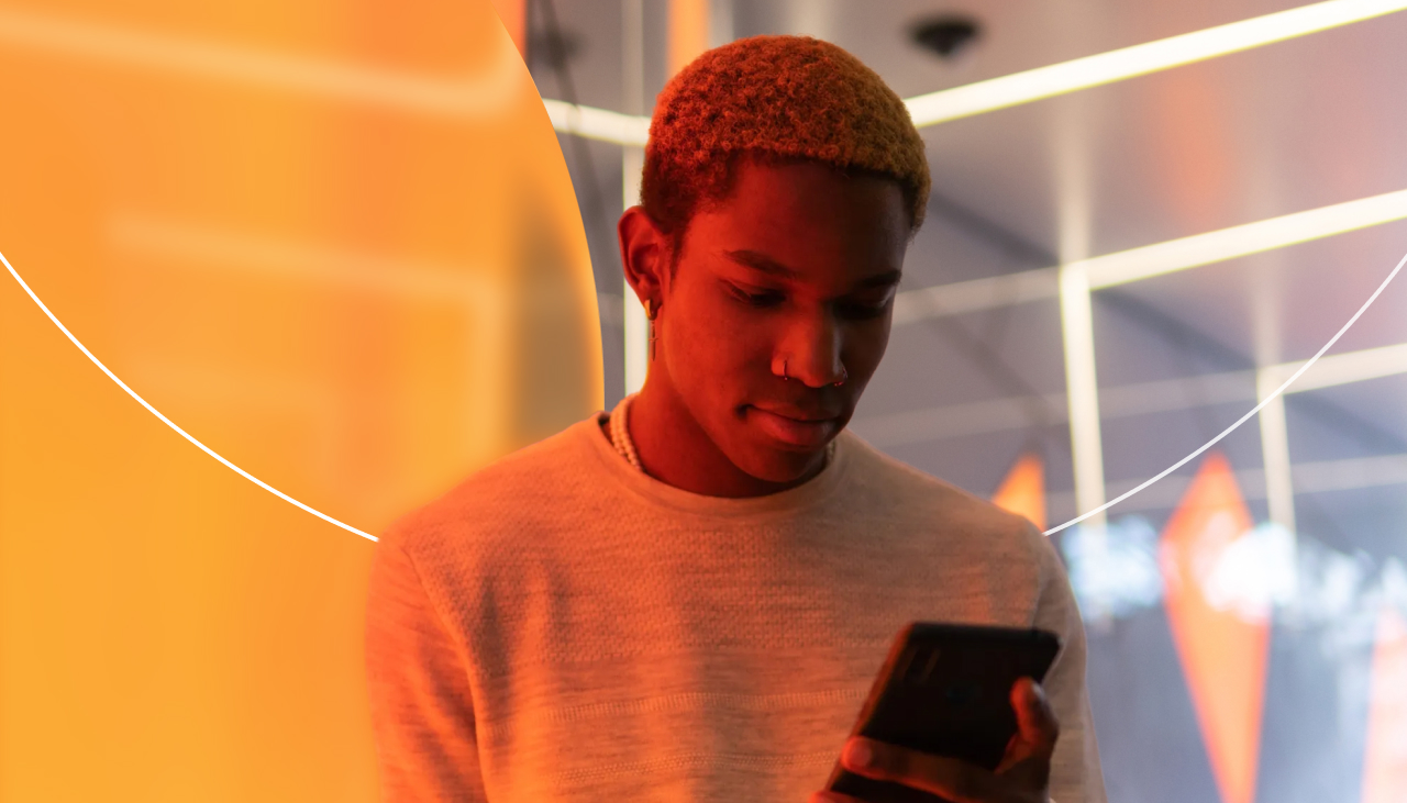 Guy looking at phone in front of orange lighting