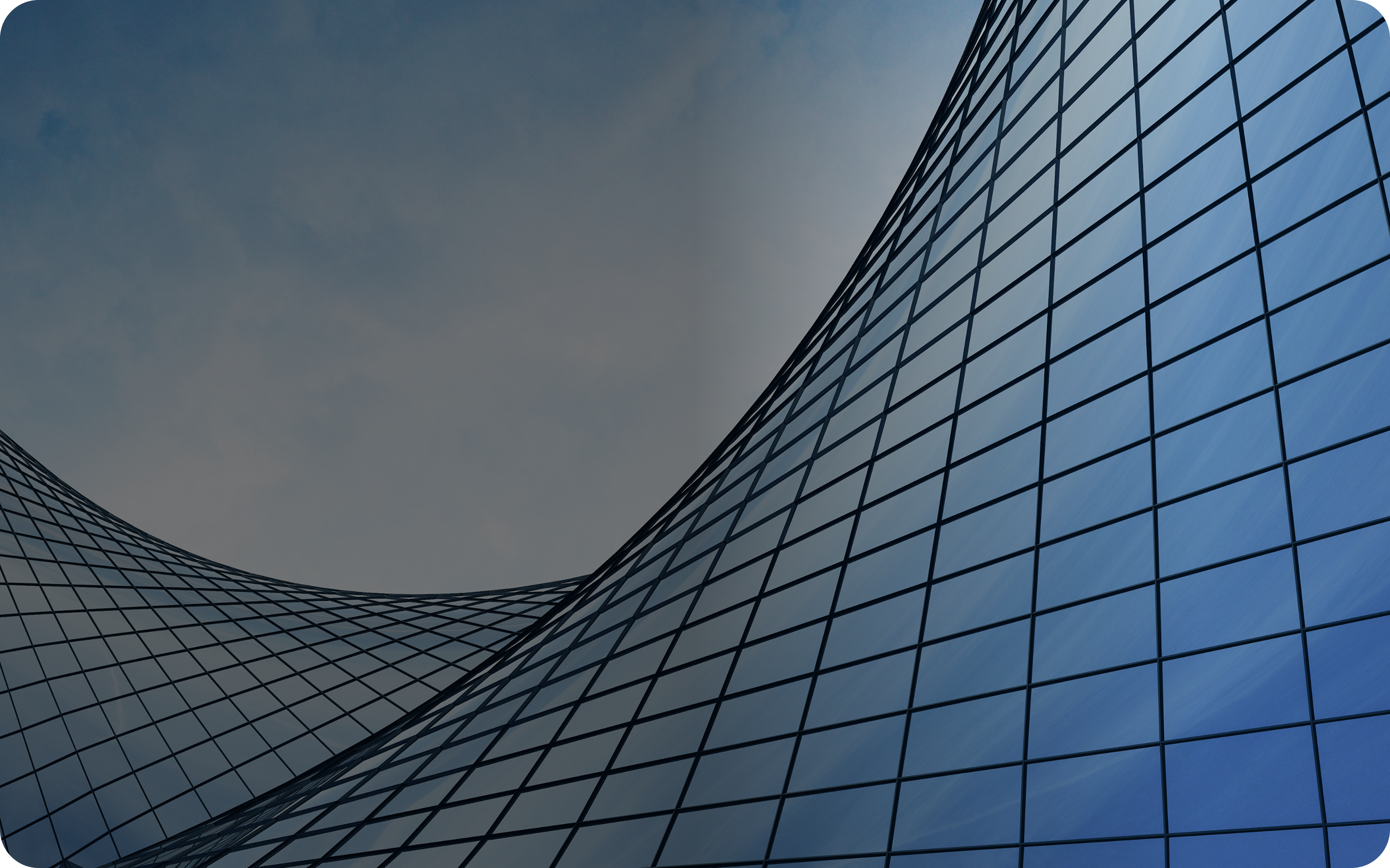 En blå bygning med en elegant, buet glassvegg som reflekterer sollys.