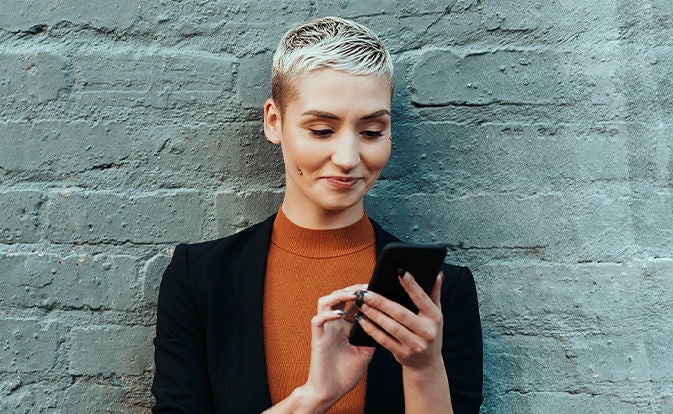 Woman in an orange sweater using her phone