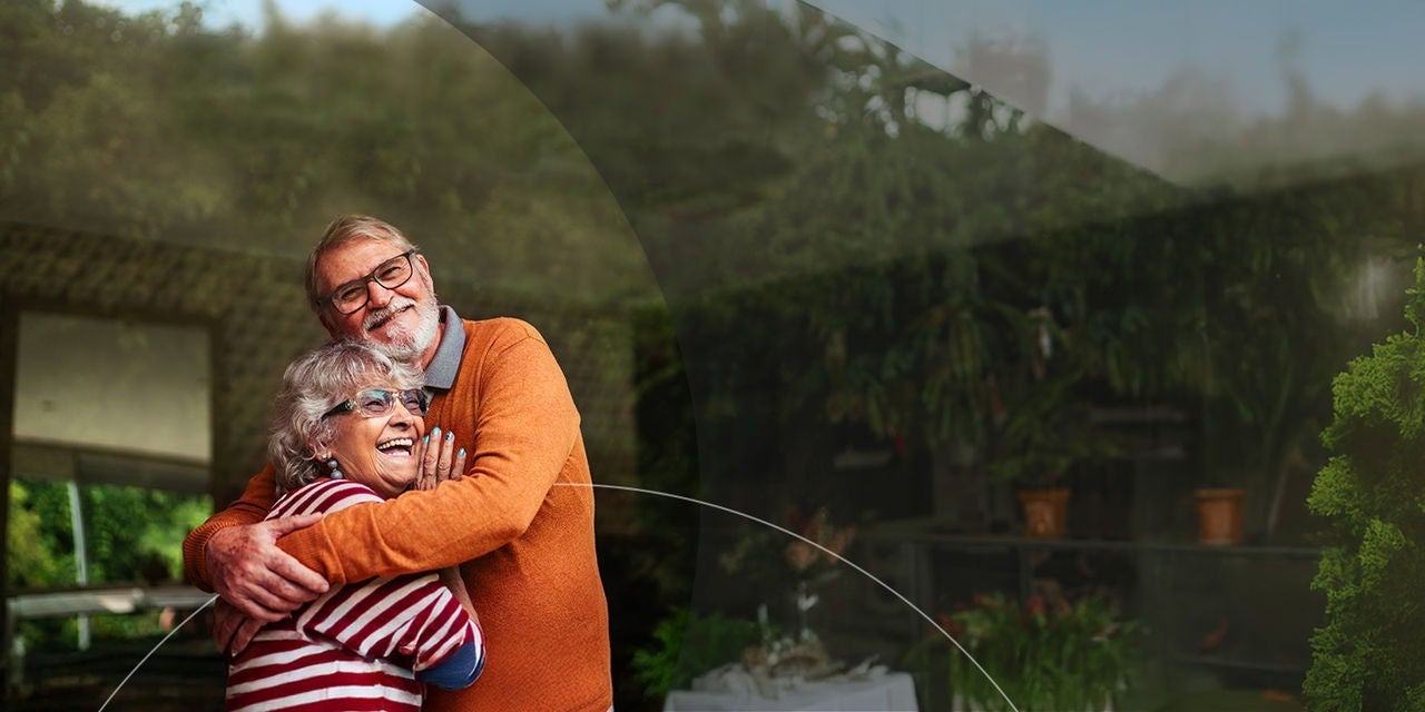 זוג קשישים מאושרים מתחבקים בחצר.