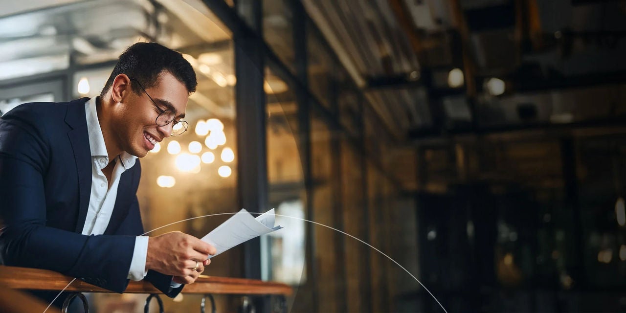 גבר לבוש חליפה ממוקד בקריאת מסמך בסביבה מקצועית.