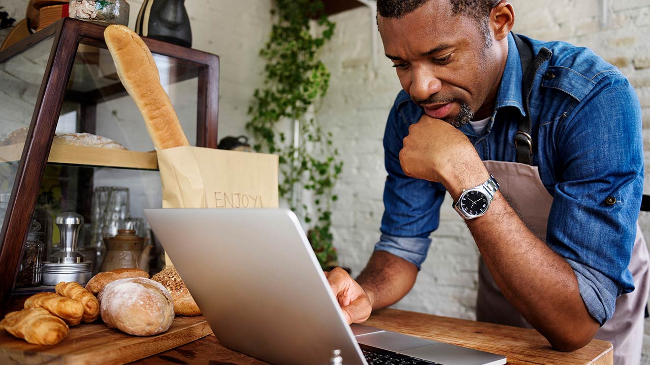 Male owner on computer at bakery.