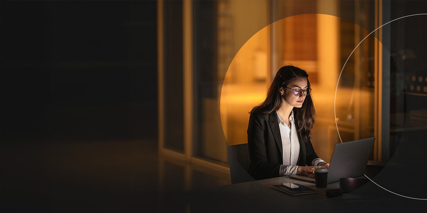 Woman working on a laptop in a dimly lit room