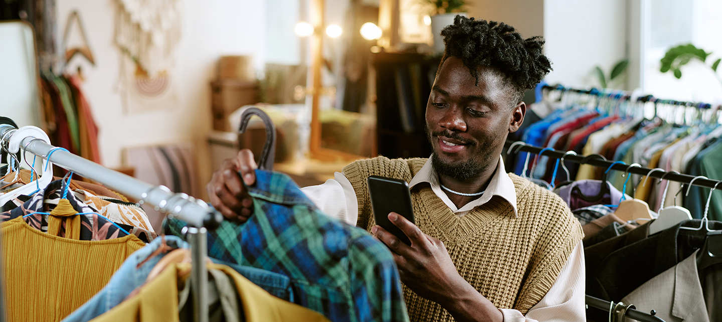 Man looking at clothes checking his phone
