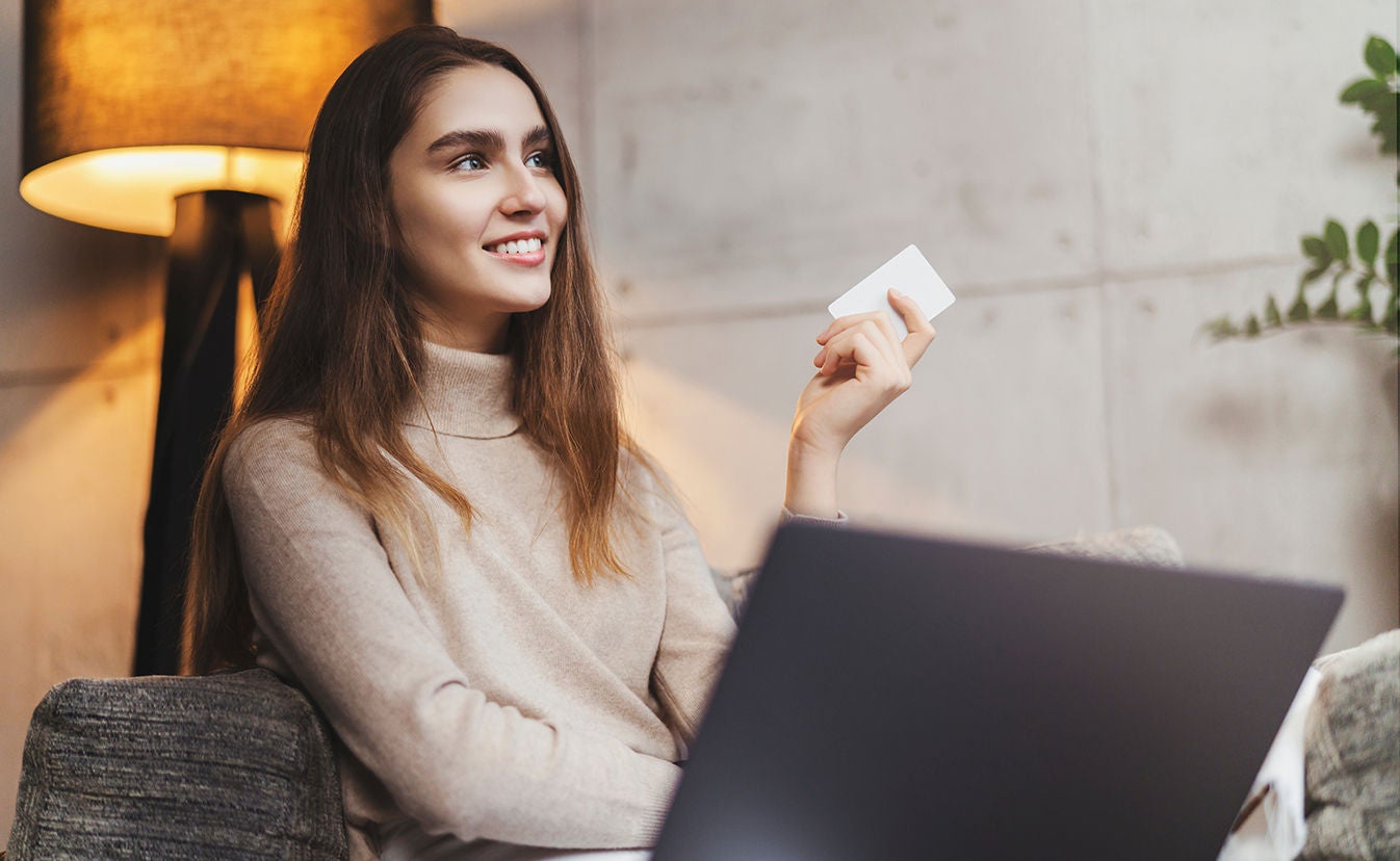 Una mujer sentada en un sofá sosteniendo una tarjeta en una mano.