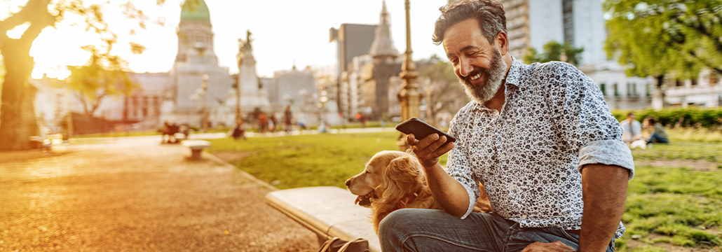 Homme souriant regardant son téléphone dans un parc
