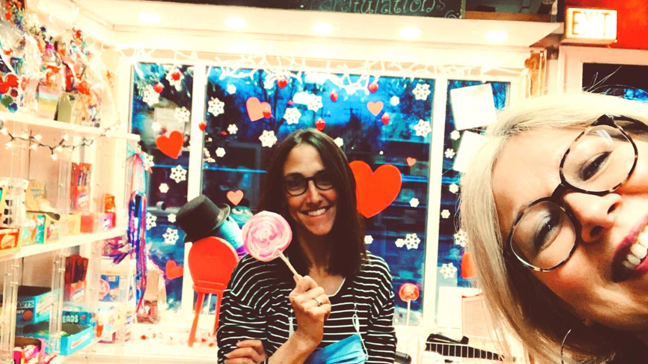 Woman holding large lolipop in candy store.