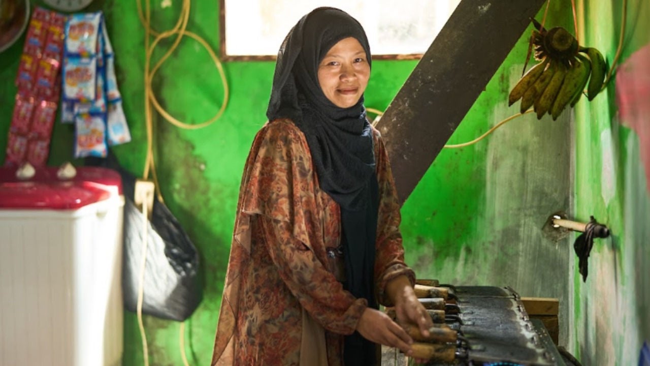 A woman smiles at her phone in her home. 