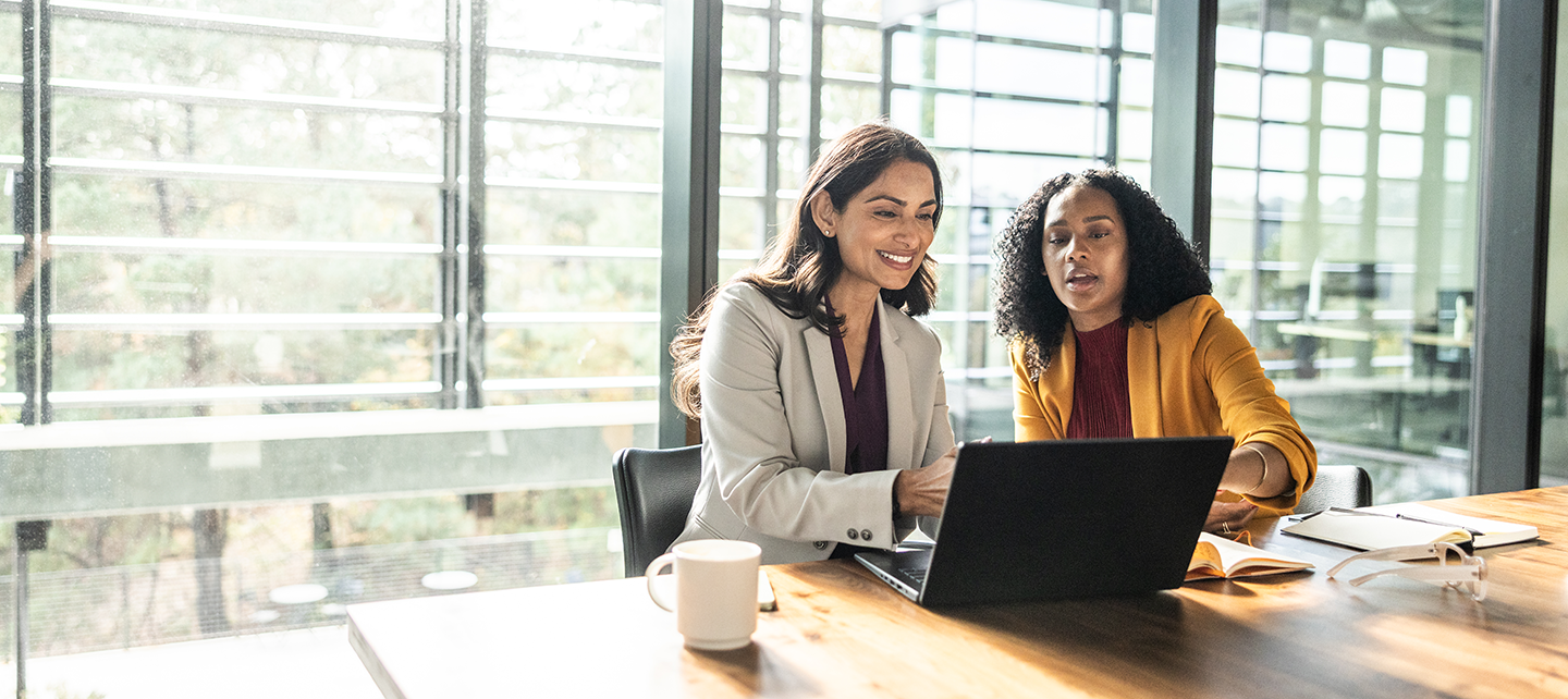 Two women reviewing insights on a laptop in the office