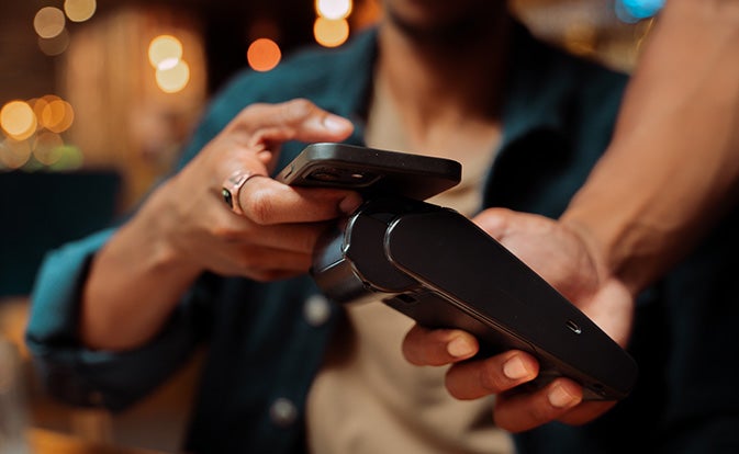 Close up of customer paying with cellular device and card machine.