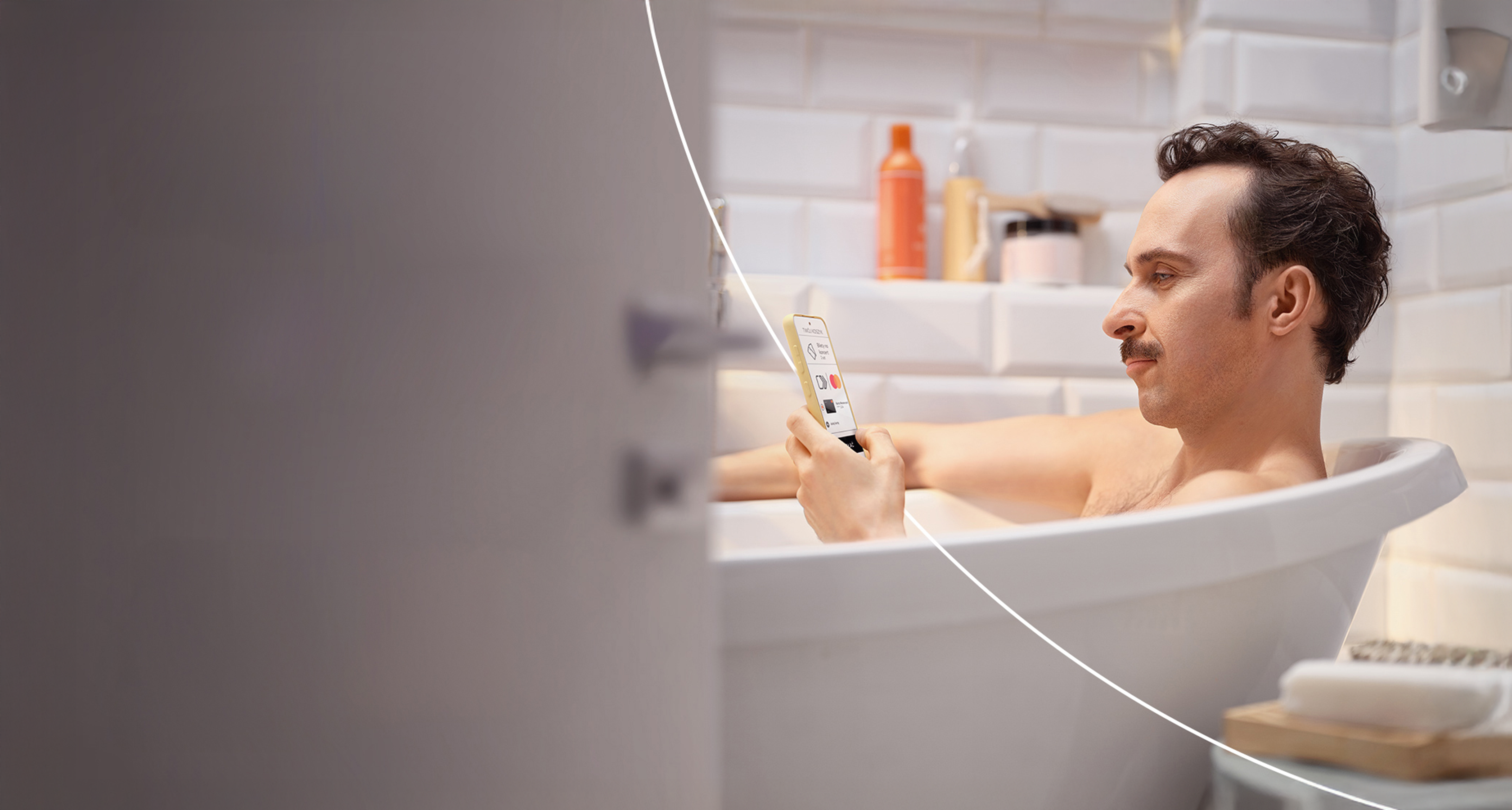 Mężczyzna relaksuje się w wannie, przeglądając telefon.