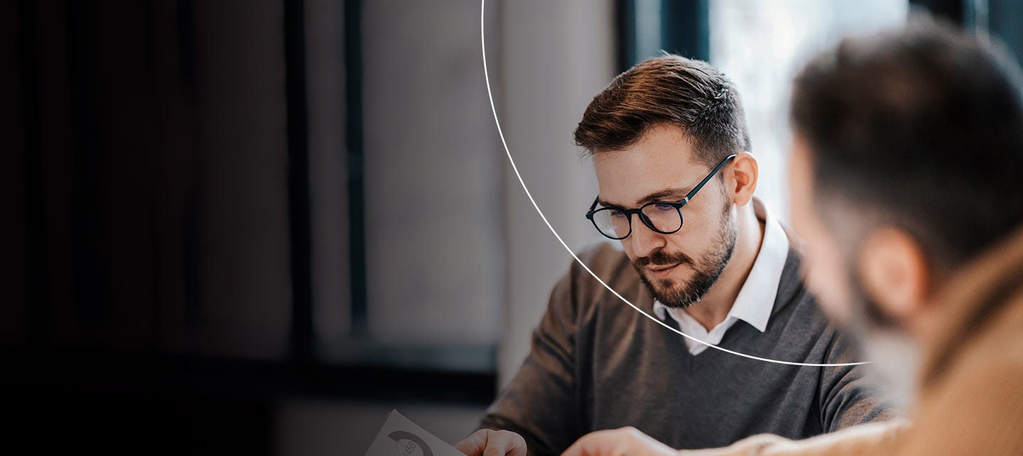 Muškarac u odijelu koncentrisan je na čitanje dokumenta u poslovnom okruženju.