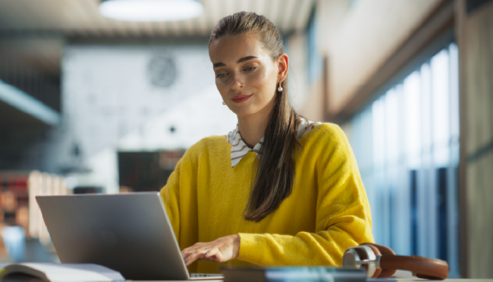 A woman in an office setting, focused on her laptop while seated at a desk