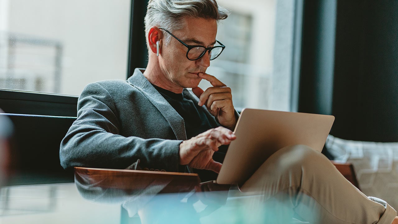 Businessman reading emails in an office lobby.
