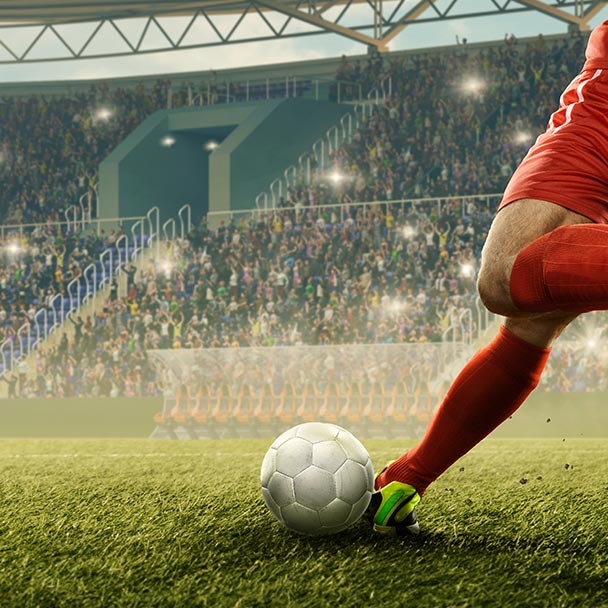 Soccer player kicking a ball on a field.