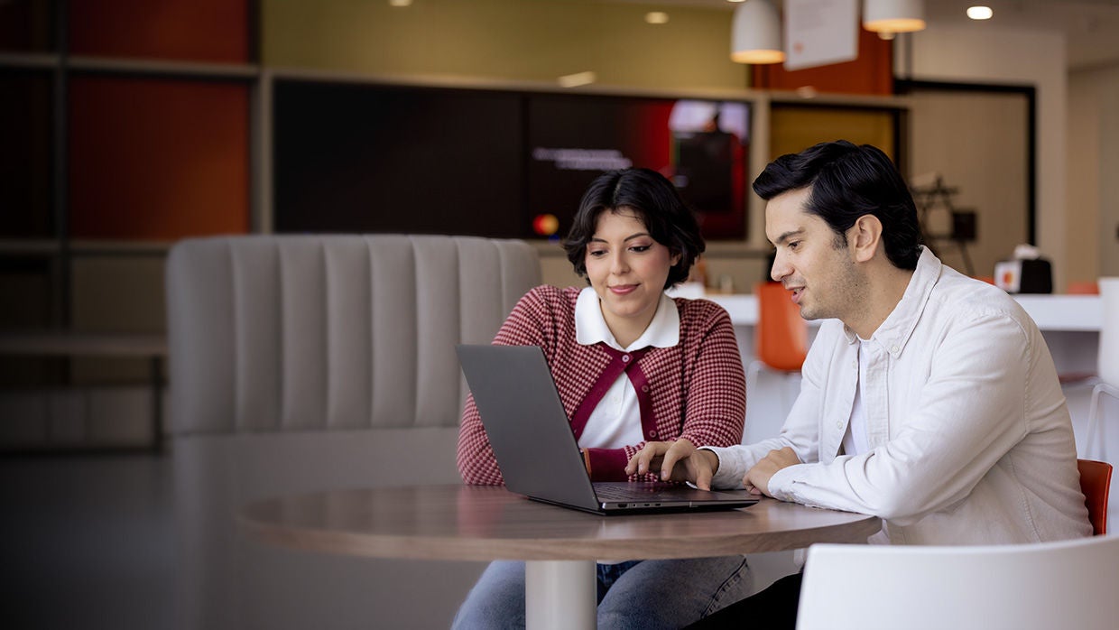 Mastercard colleagues working on laptop in cafeteria.