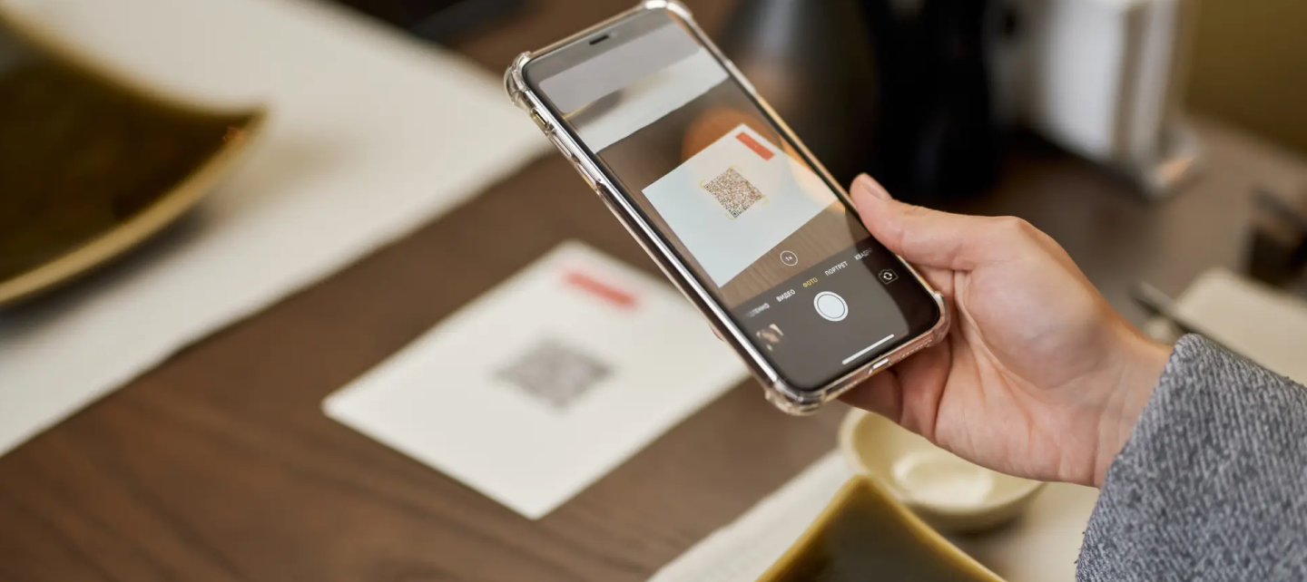 A person holding a phone pointing at QR code 