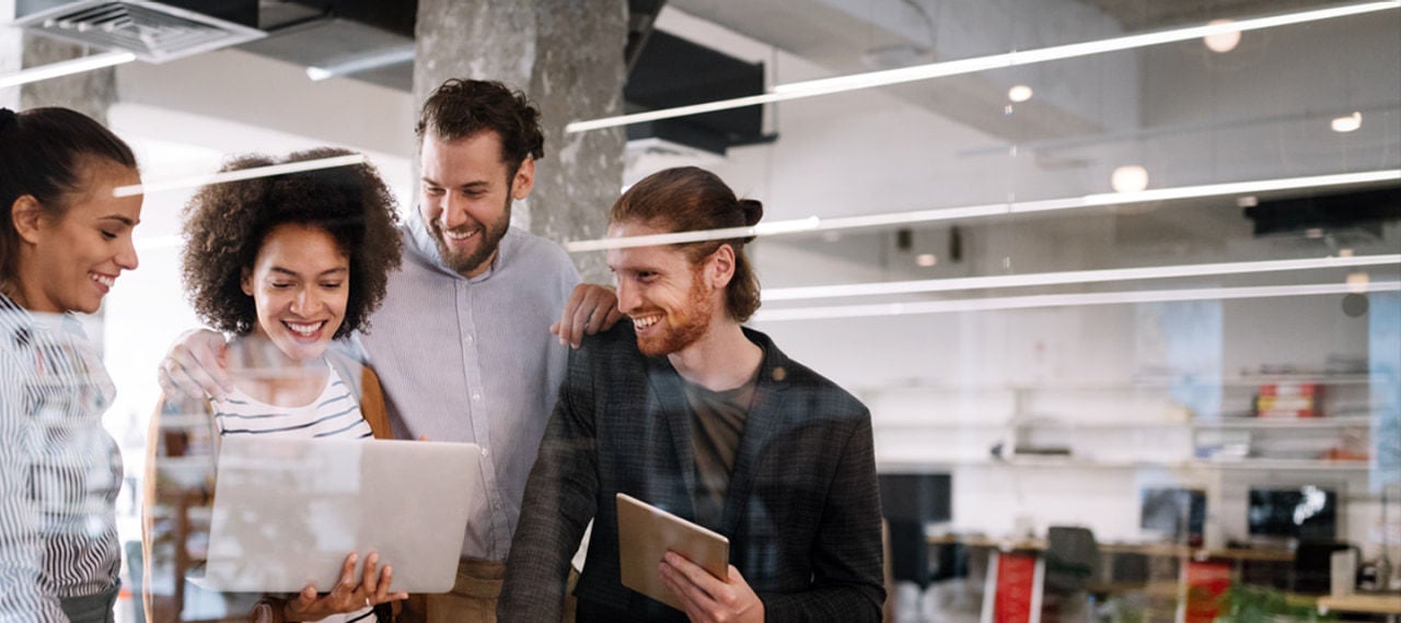 مجموعة متنوعة من الأشخاص اجتمعت حول حاسوب محمول، منخرطين في نقاش وينظرون إلى الشاشة معًا.