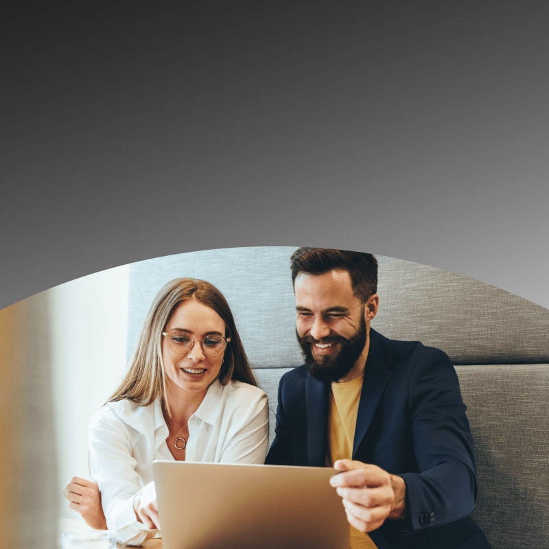 smiling colleagues looking at laptop