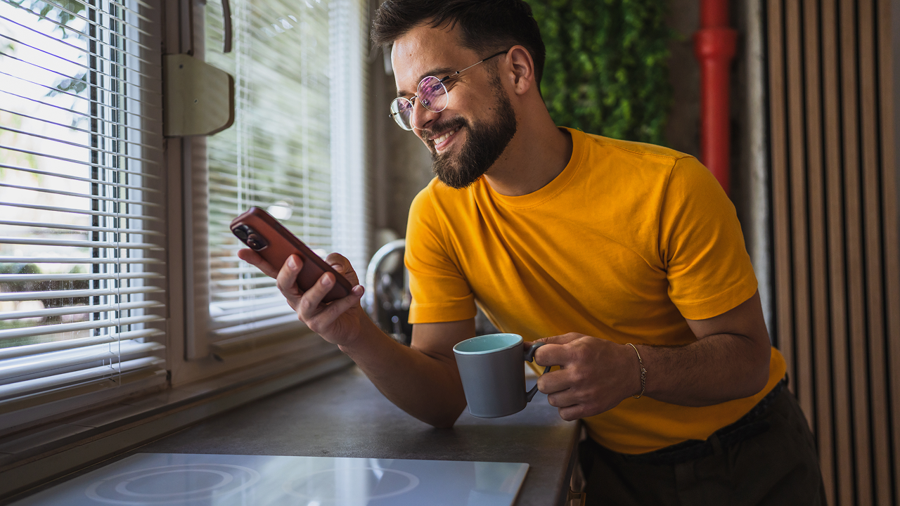 A man in a yellow shirt is looking at his cell
