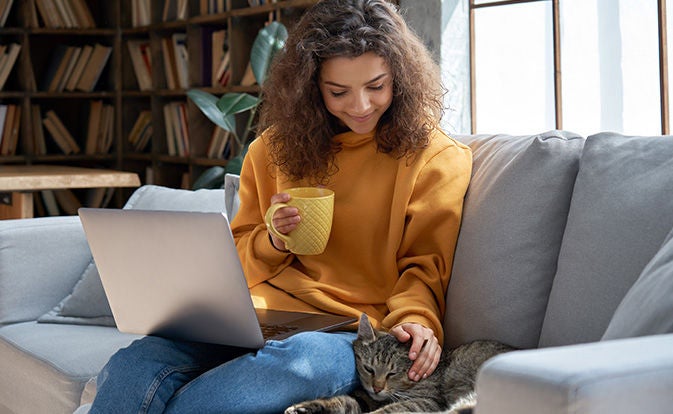 Relaxed girl sitting on couch laptop on lap.