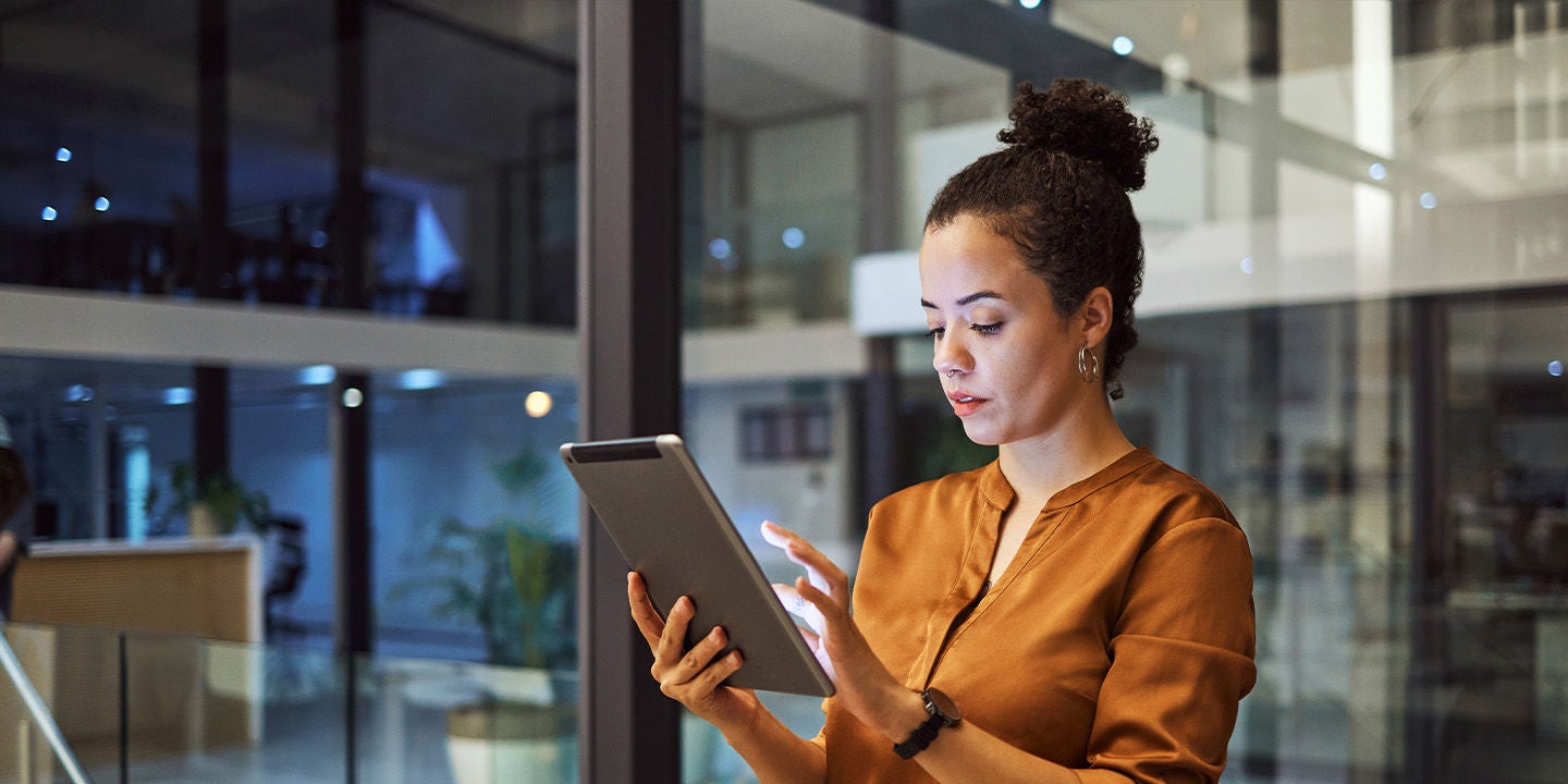 Woman in an orange shirt using a tablet at work