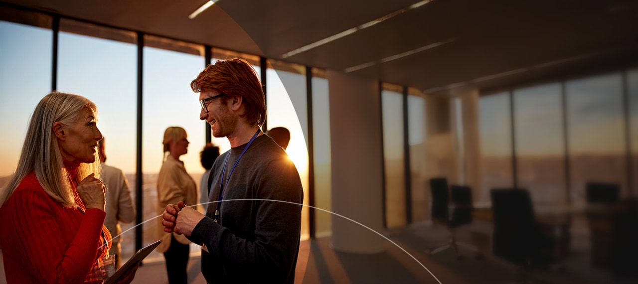 גבר ואישה מנהלים שיחה במשרד שטוף שמש.