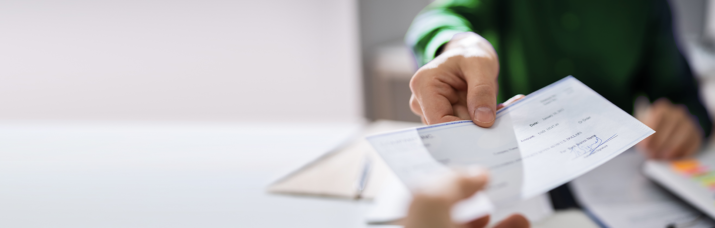 Person handing check to teller at a bank